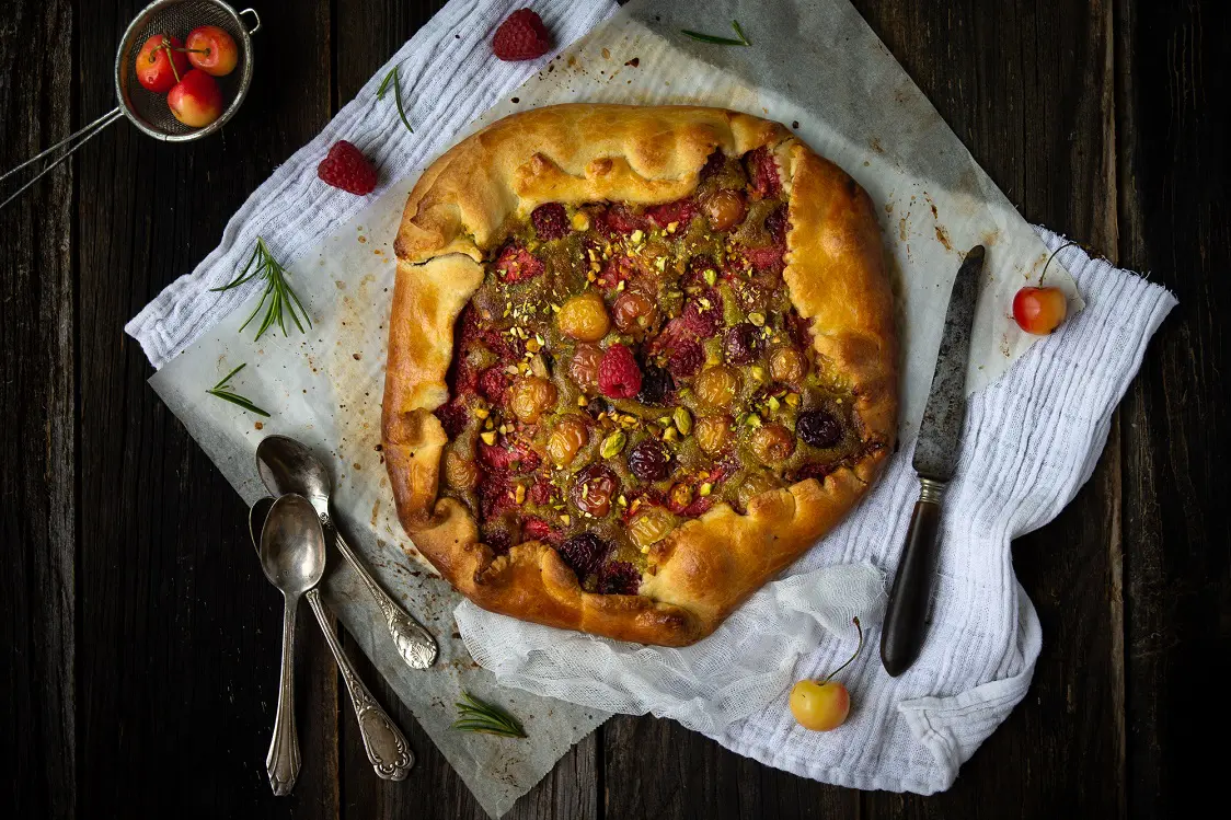 la recette d'une tarte rustique avec une creme d'amande et pistache, des fraises, des framboises et des cerises - par Confit Banane